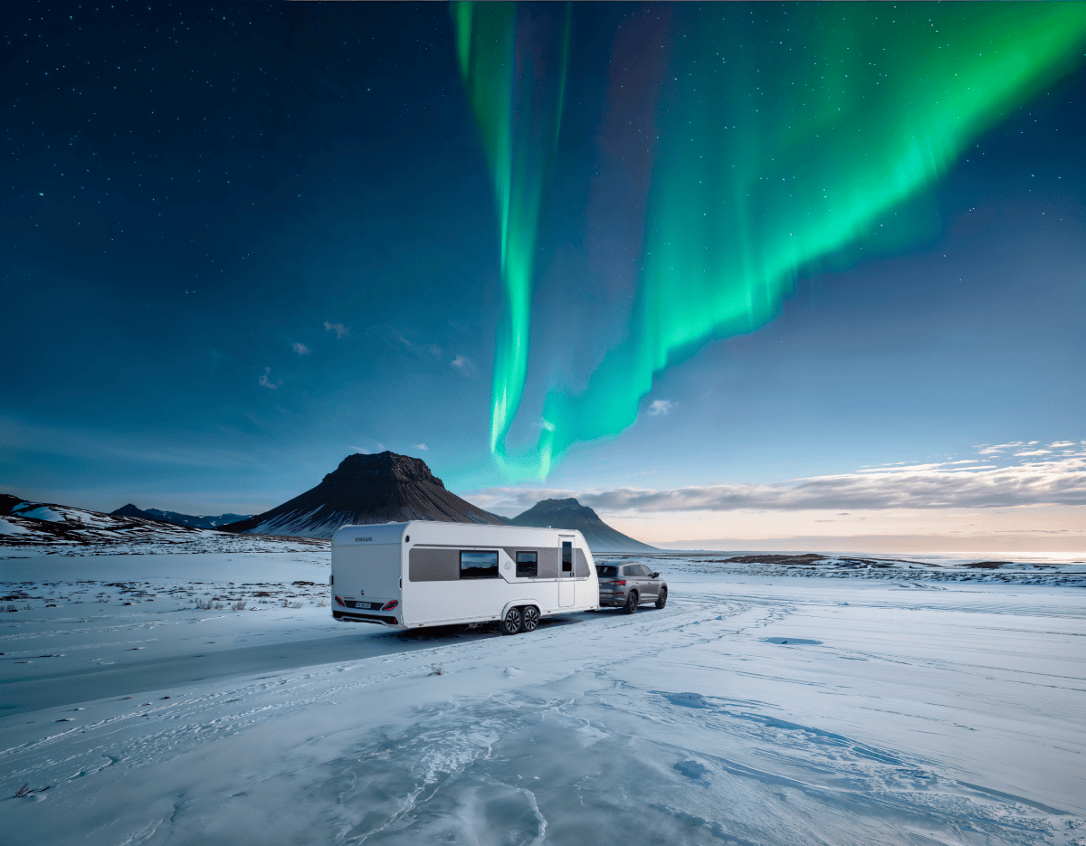 Knaus Nordwind caravan, modeljaar 2027, in de sneeuw met het noorderlicht op de achtergrond.