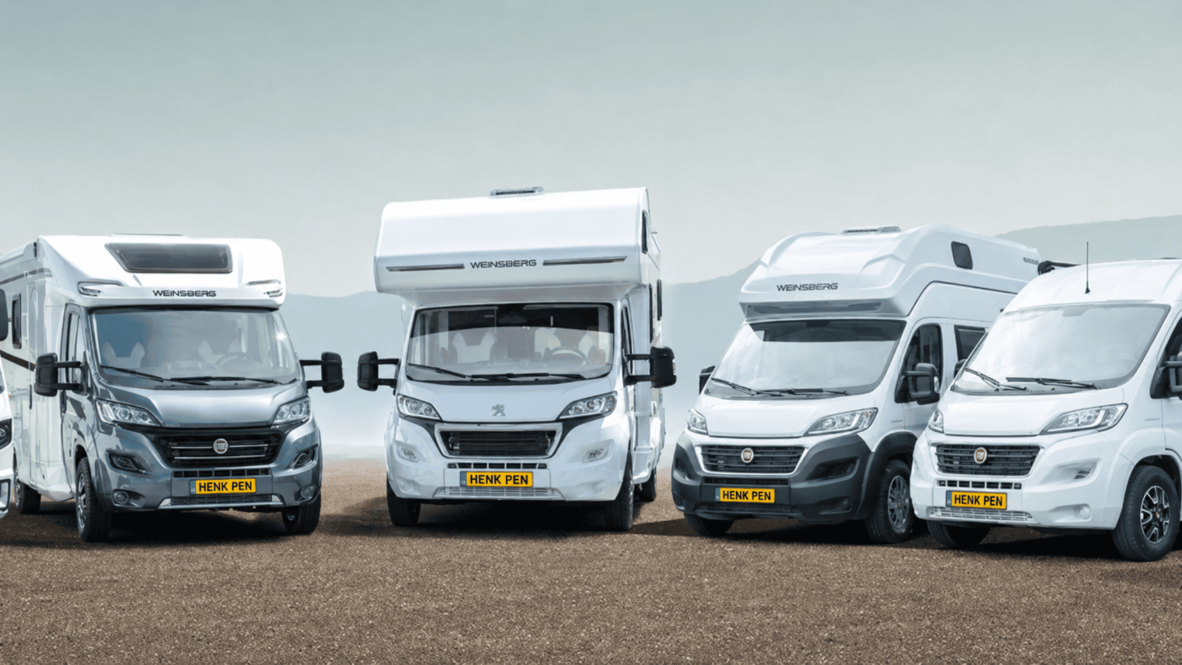 Vier campers met kentekenplaat Henk Pen geparkeerd op een onverharde weg, omringd door groene natuur.