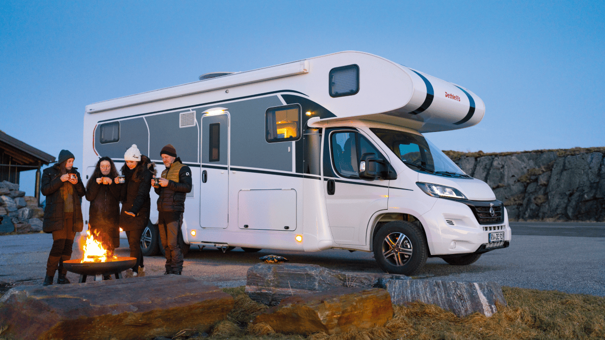 Een familie staat bij een alkoof camper, enthousiast voor hun vakantie samen.