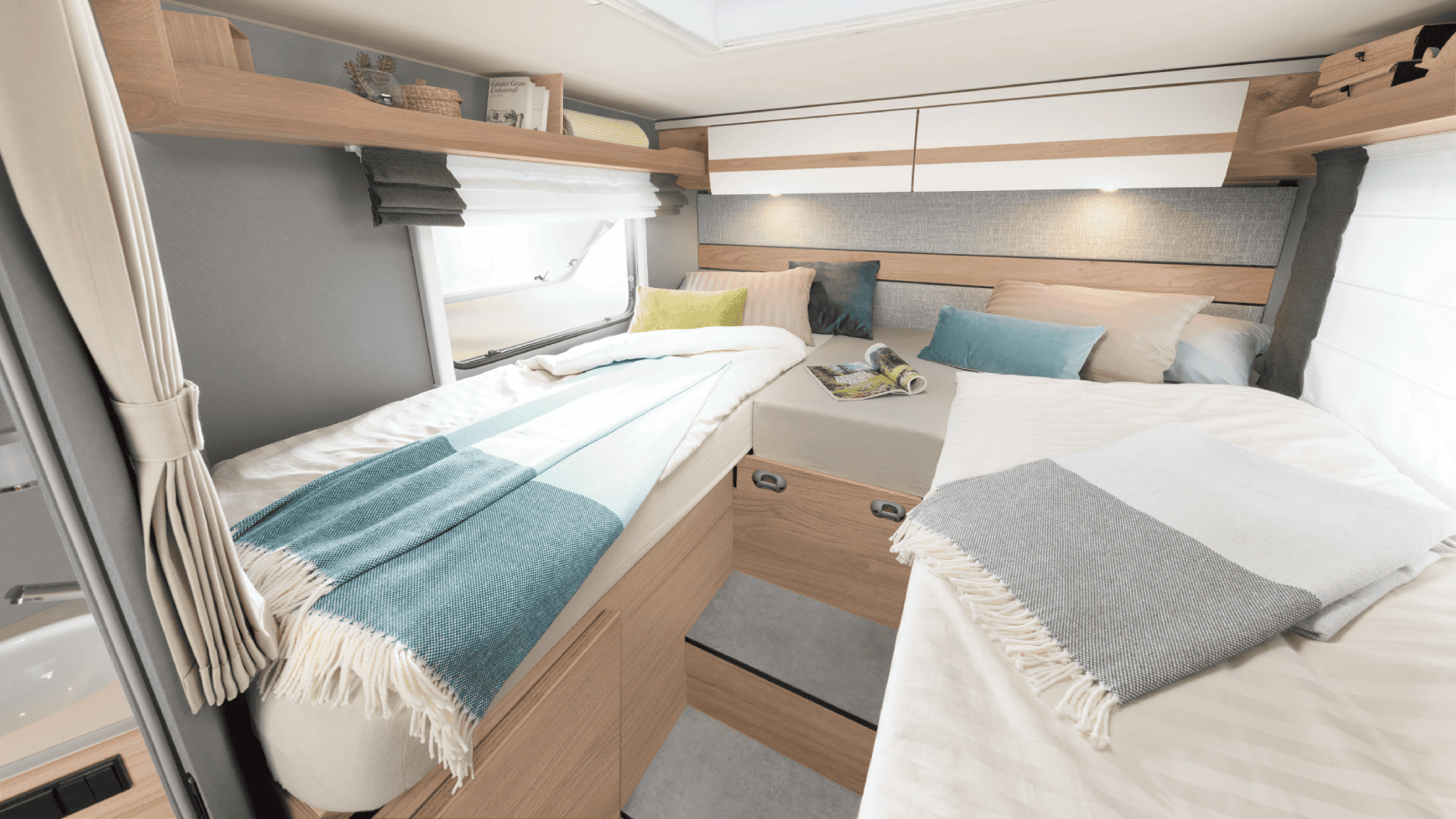 Bedden in een camper met een opstapje en uitschuifstuk voor bedverbreding in het midden van de ruimte