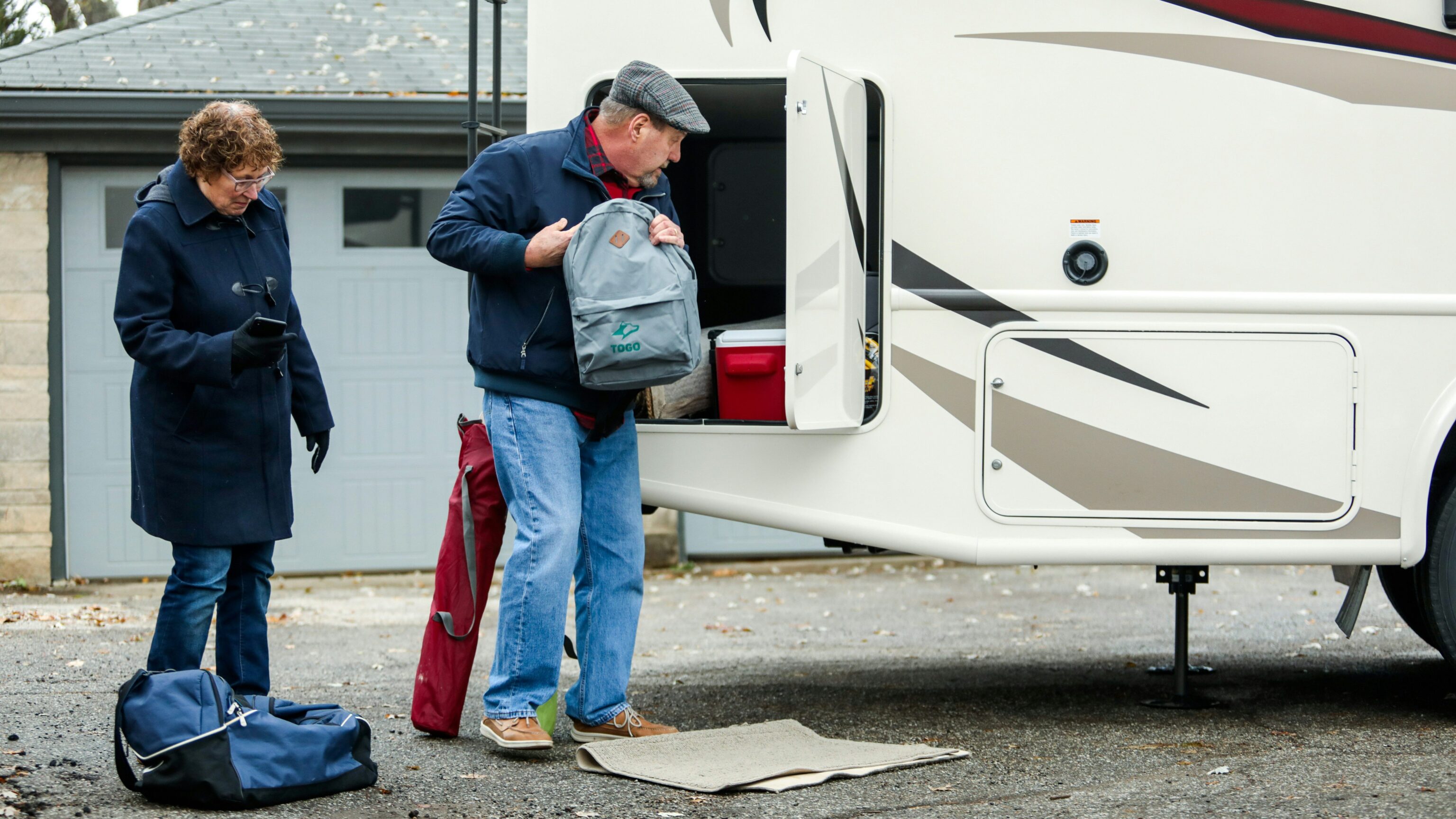 Een man en vrouw zijn bezig met het inladen van bagage in een camper voor hun avontuur.